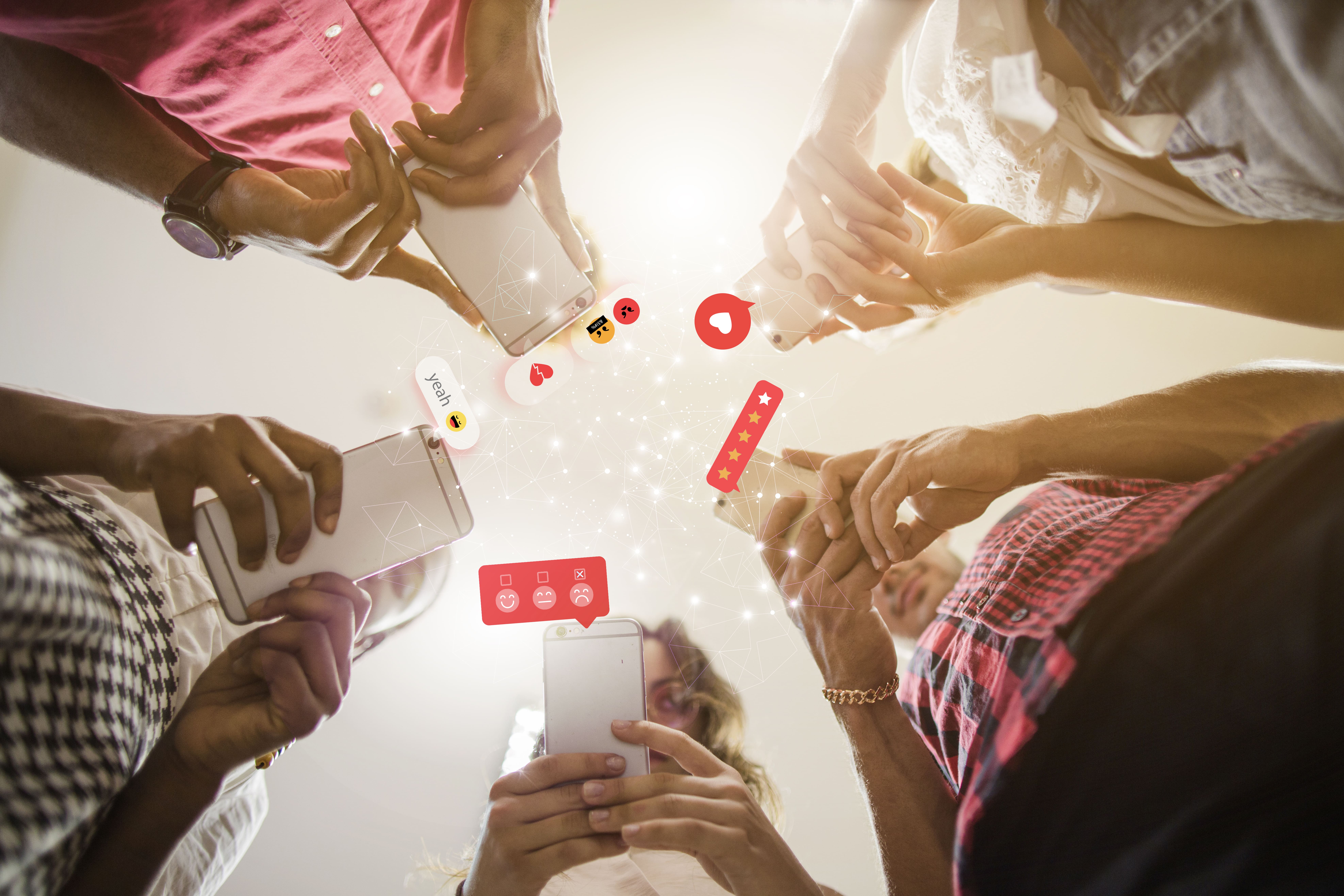 5 personnes sur leur téléphone. Des icônes illustrant les réseaux sociaux sont affichées autour du téléphone.